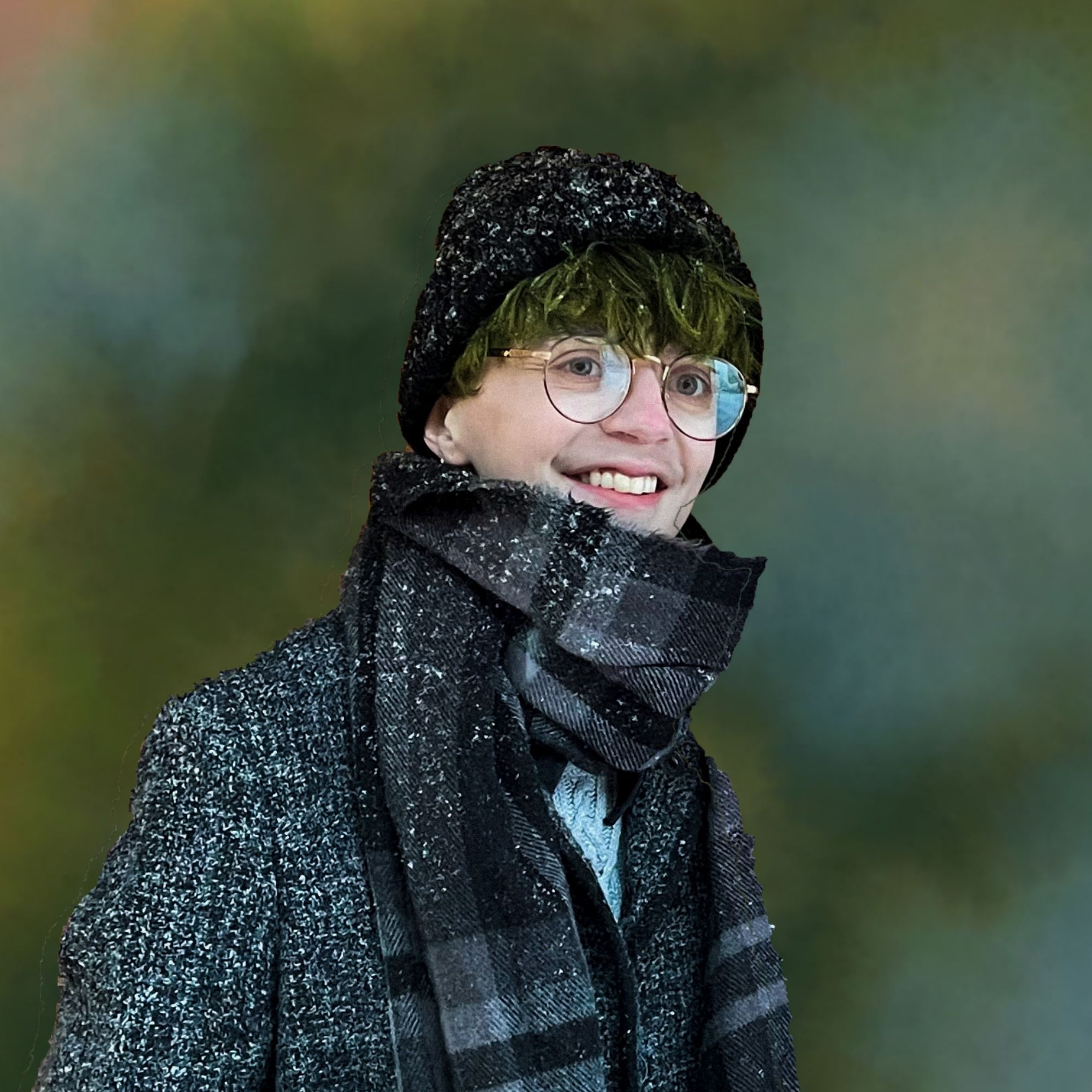 Mad Marshall portrait, fair-skinned person with glasses smiles and wears a coat, scarf, and hat in front of a blurred background